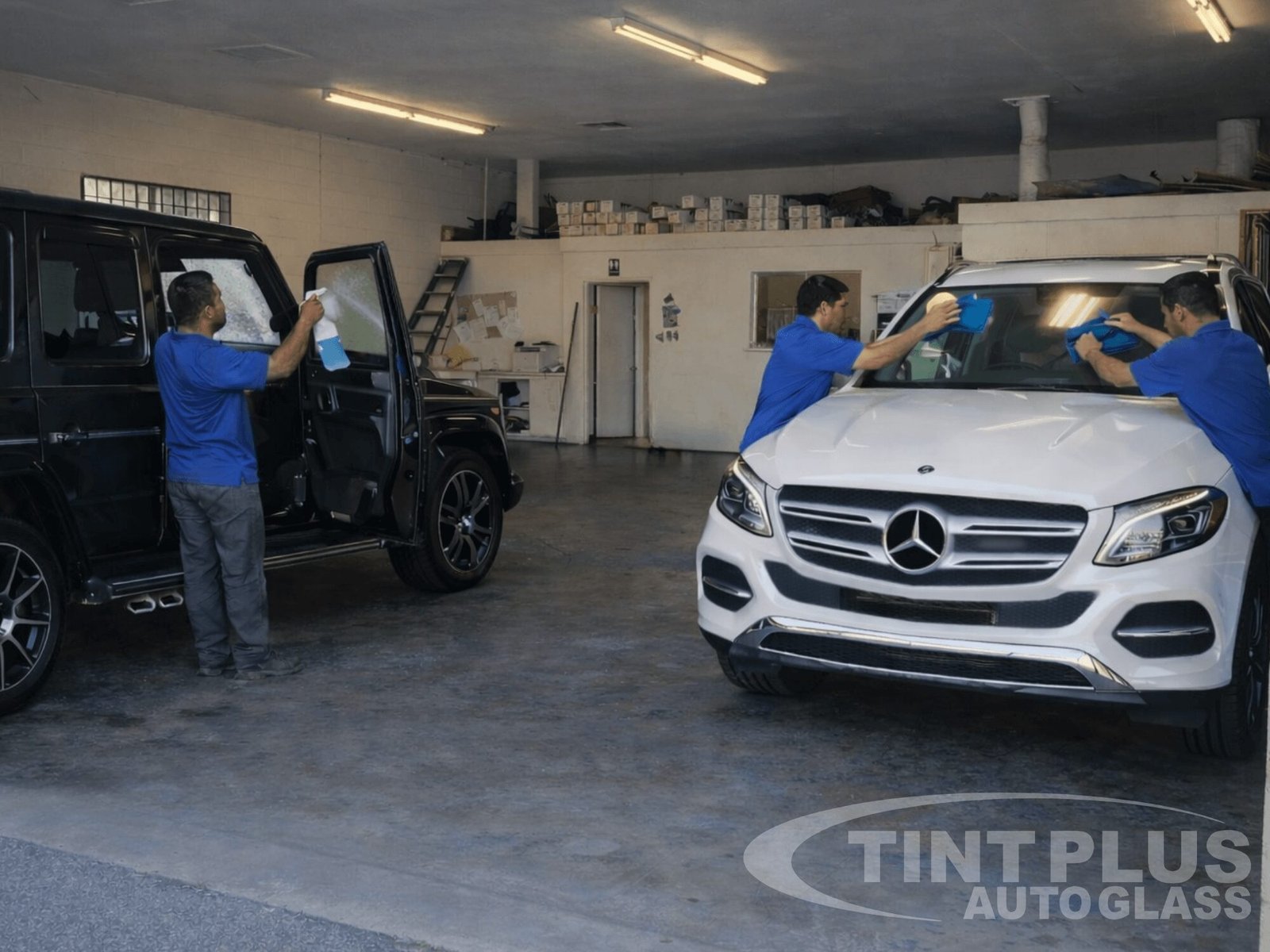 Technicians at Tint Plus Auto Glass in Hanford CA installing and cleaning window tint on a Mercedes SUV inside a professional auto glass workshop. Technicians at Tint Plus Auto Glass in Hanford CA installing and cleaning window tint on a Mercedes SUV inside a professional auto glass workshop.